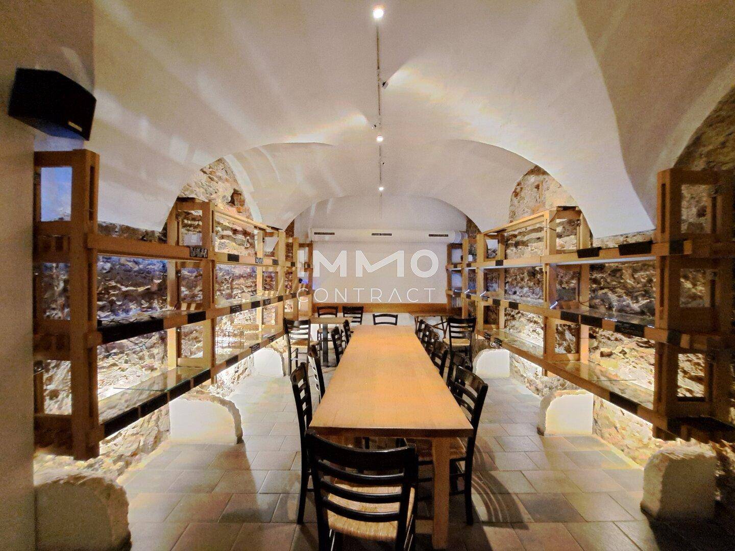 Historischer Gewölbekeller mit langer Holztafel, Steinwänden und indirekter Beleuchtung, ideal für Veranstaltungen.