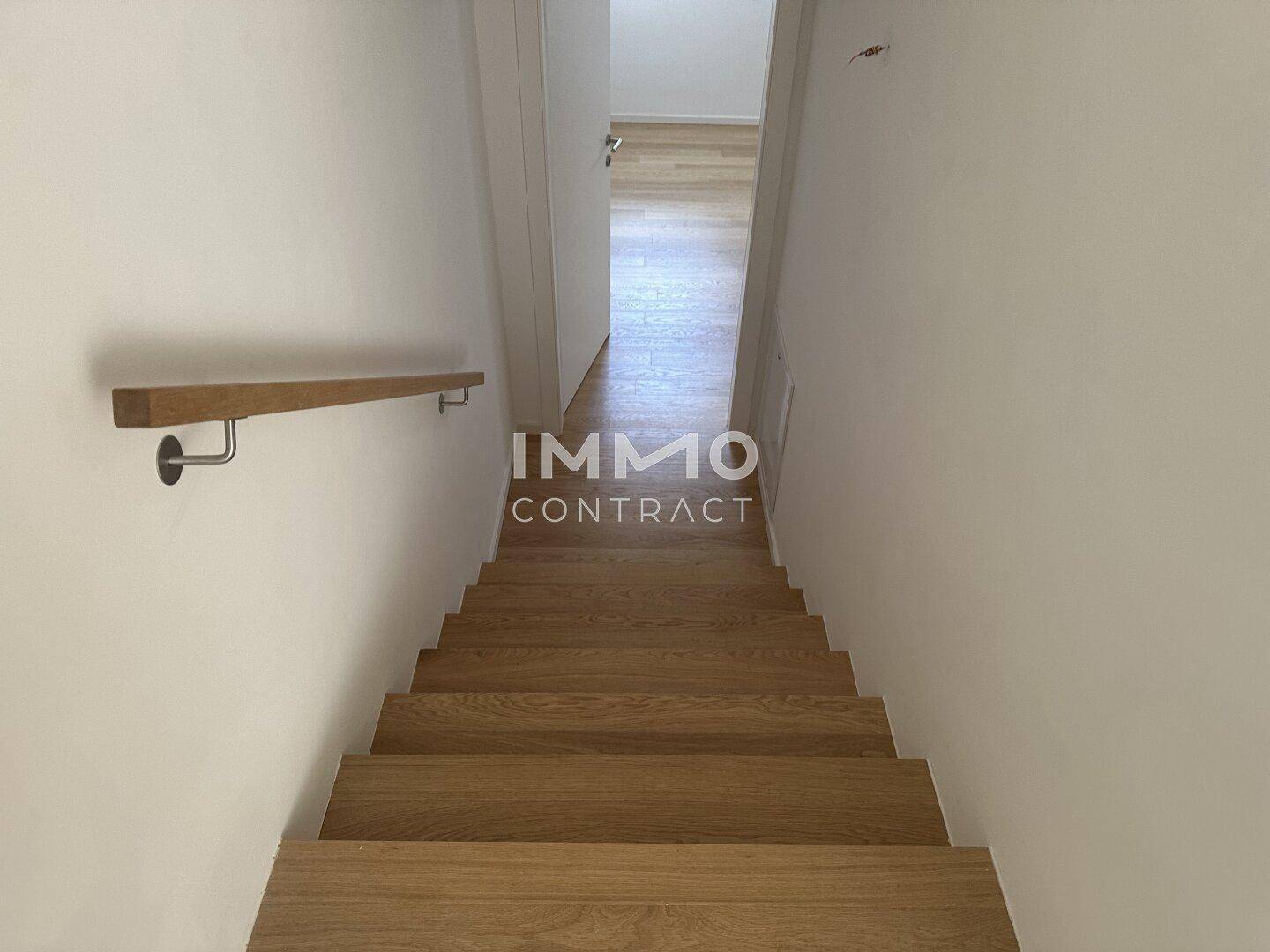 Helle Holztreppe mit modernem Handlauf, die die verschiedenen Ebenen der Wohnung verbindet.