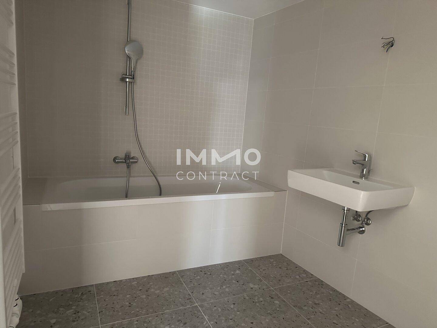 Modernes Badezimmer mit Badewanne, Waschbecken und beheiztem Handtuchhalter, in hellen Farbtönen gehalten.