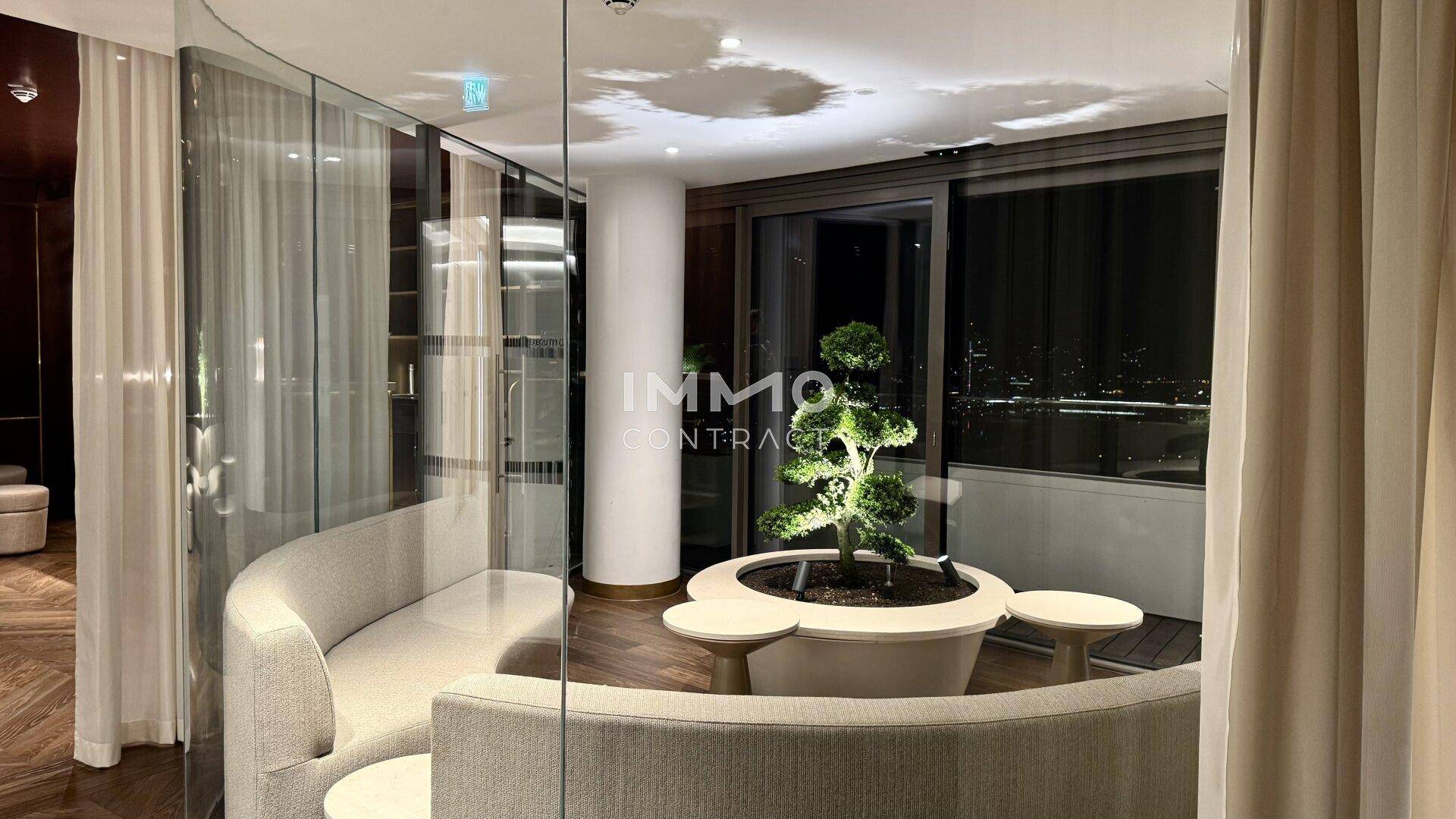 Gemütlicher Loungebereich mit geschwungenen Sofas und Blick auf die nächtliche Stadt.