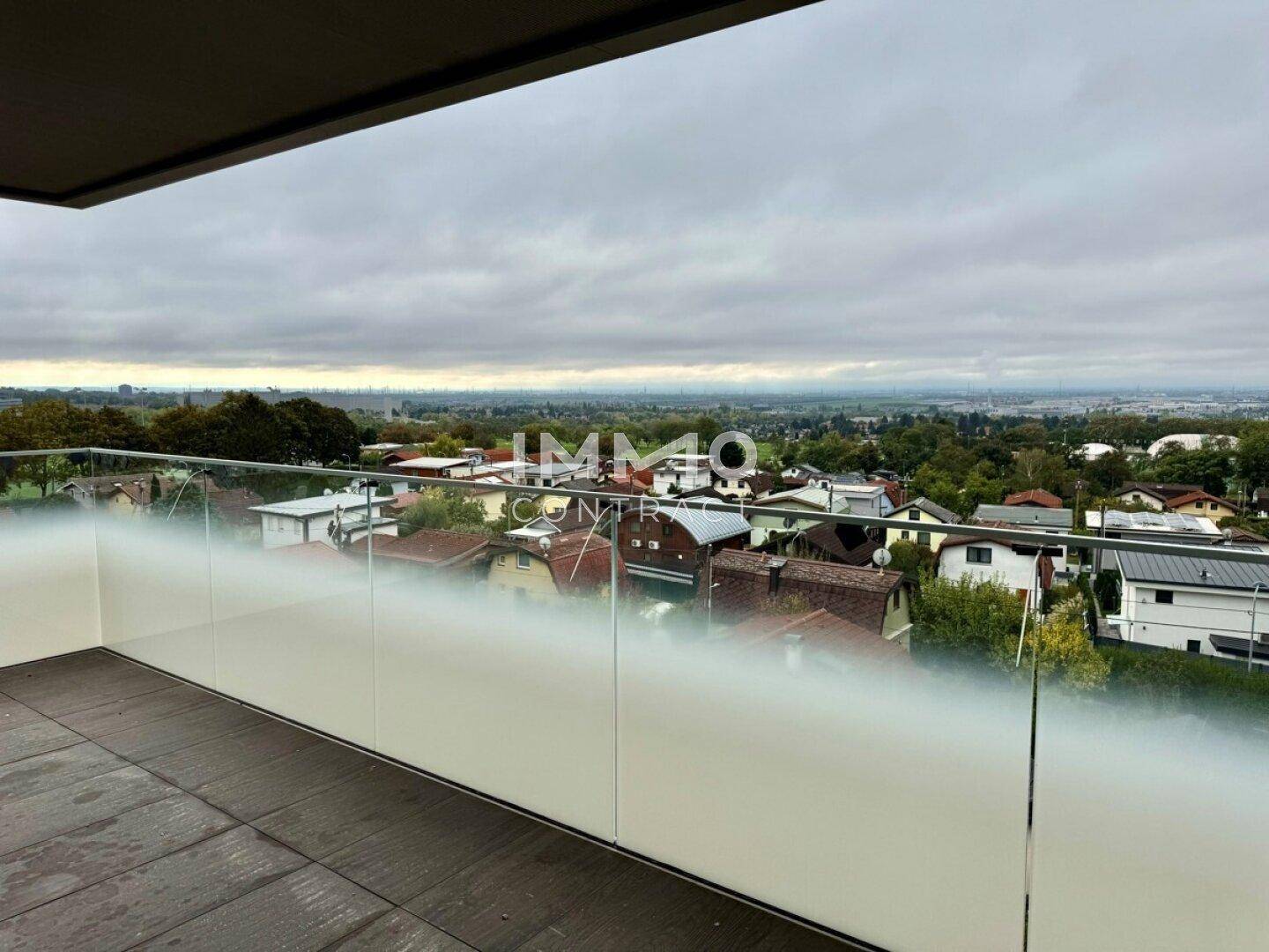 Moderner Balkon mit Glasgeländer und Panoramablick auf die umliegende Landschaft.