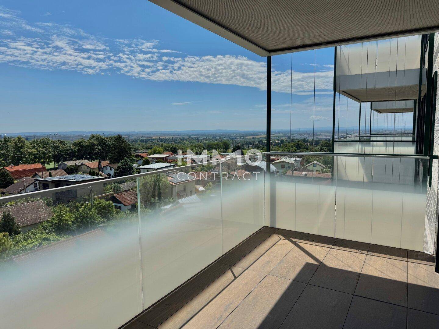 Geräumiger Balkon mit Glasbrüstung und weitem Blick über die umliegende Landschaft.