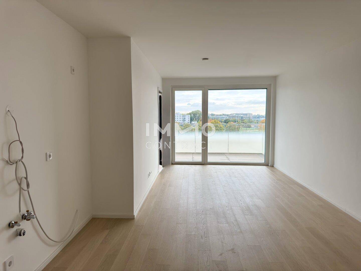 Heller, leerer Raum mit Holzboden und Zugang zu einem Balkon, ideal für Wohn- oder Essbereich.