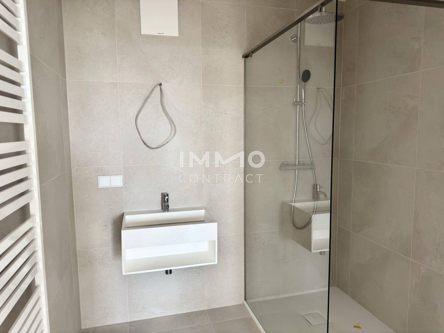 Modernes Badezimmer mit schwebendem Waschtisch, ebenerdiger Dusche und beheiztem Handtuchhalter.