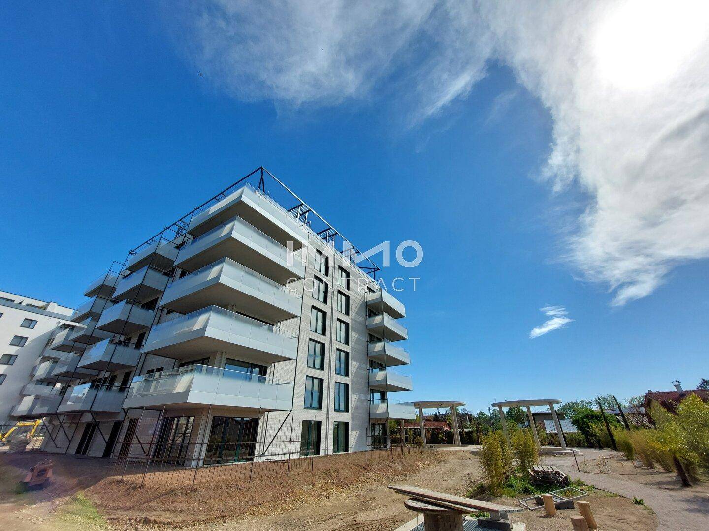 Moderne Wohnanlage mit markanten Balkonen und zeitgenössischer Architektur unter blauem Himmel.