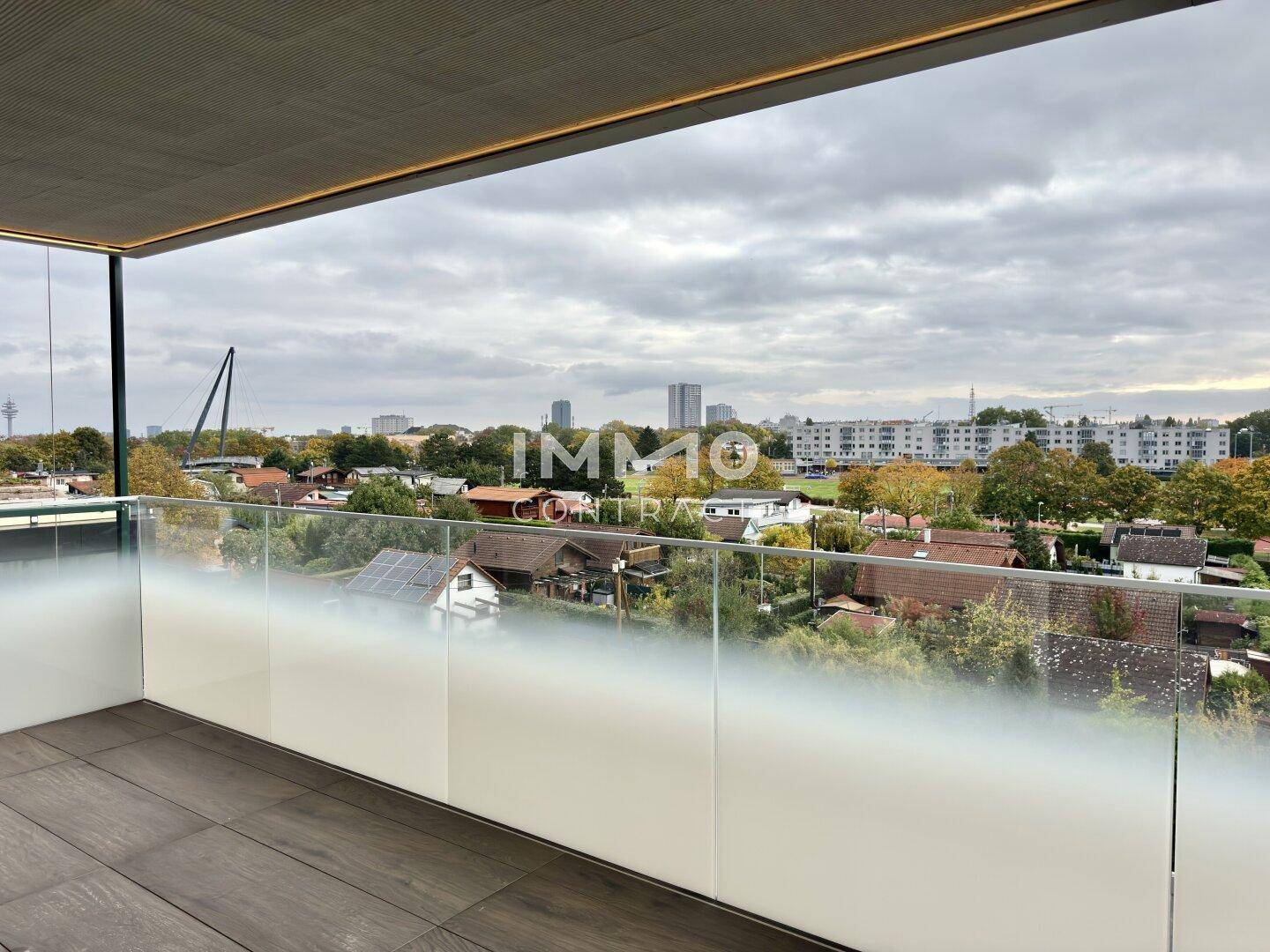 Balkon mit moderner Glasbrüstung und Blick auf die Stadt und die umliegende Bebauung.