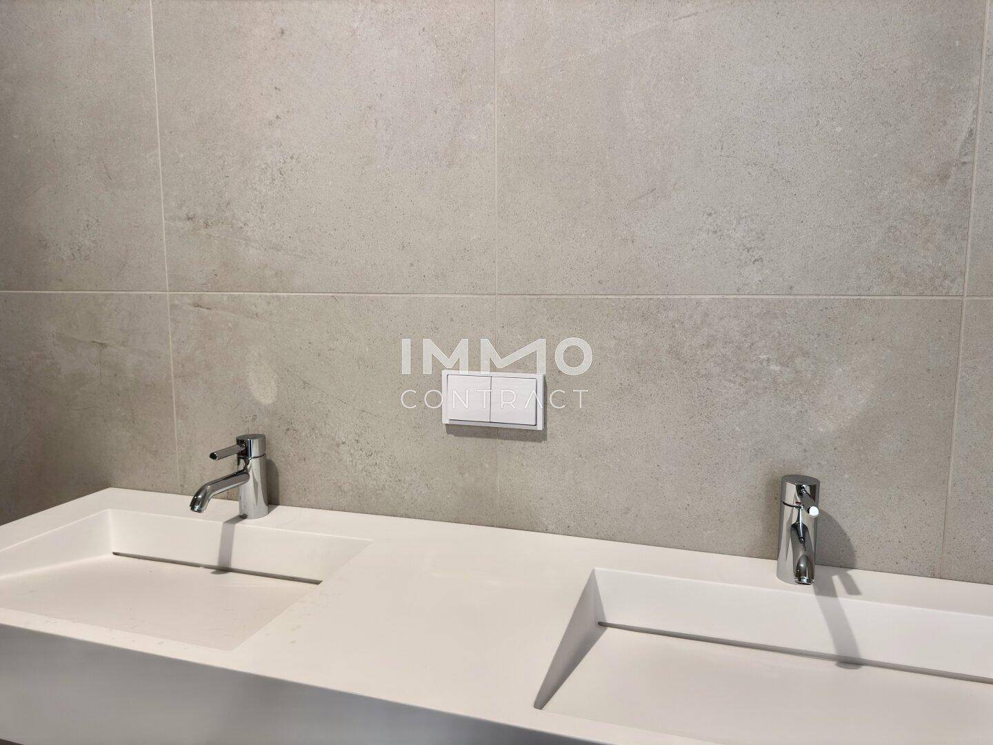 Modernes Badezimmer mit Doppelwaschbecken und großformatigen Fliesen an den Wänden.