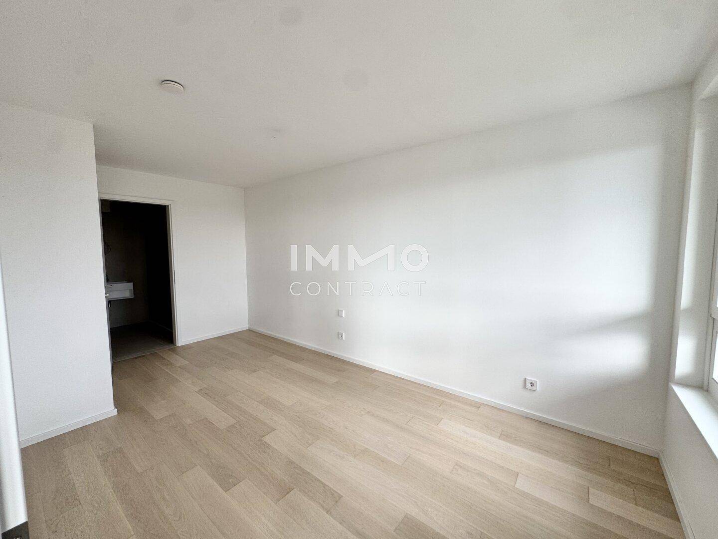 Lichtdurchfluteter Raum mit Parkettboden und großen Fenstern, ideal für Wohnzwecke.