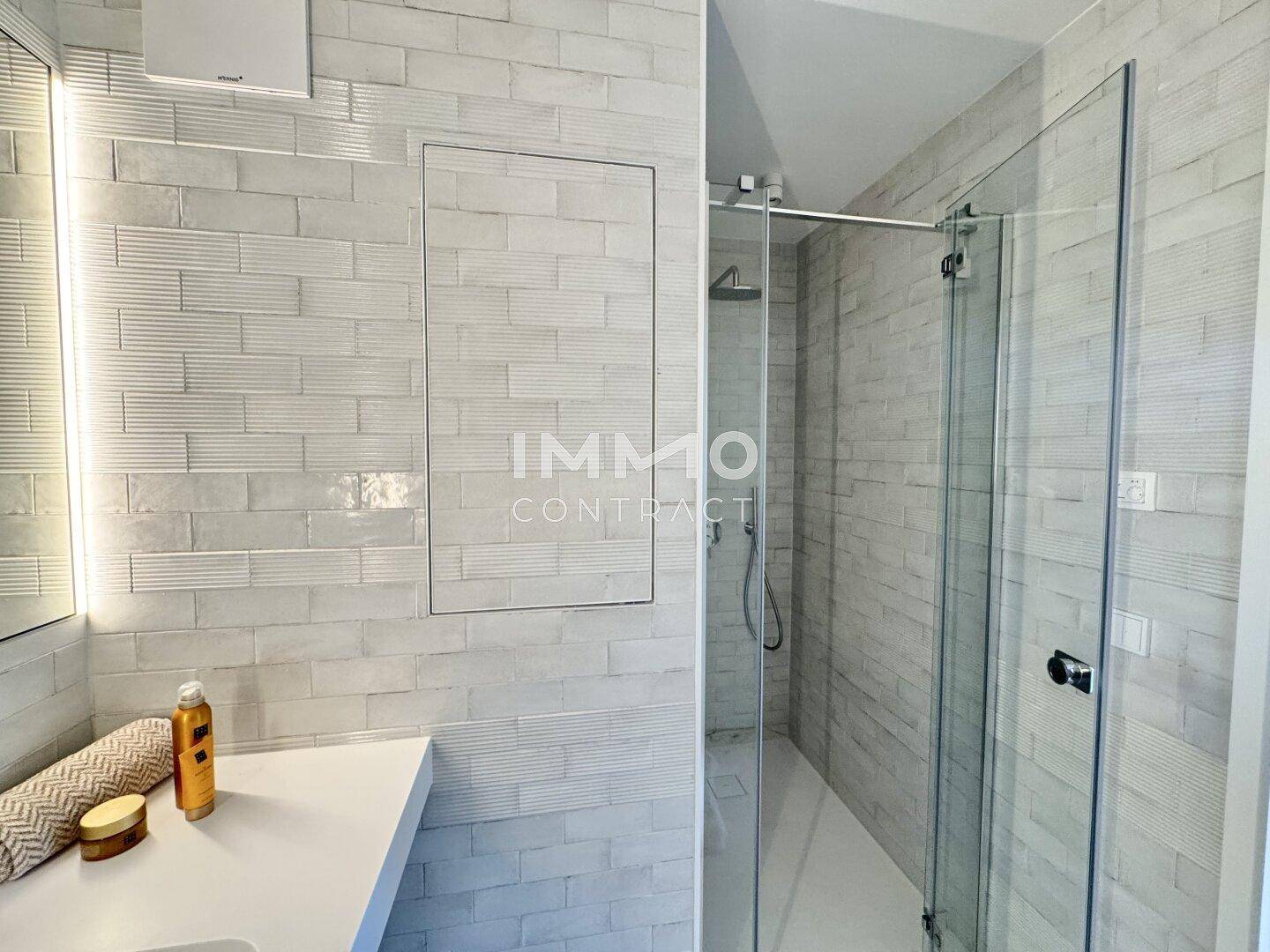 Modernes Badezimmer mit begehbarer Dusche und stilvollen weißen Fliesen an den Wänden.