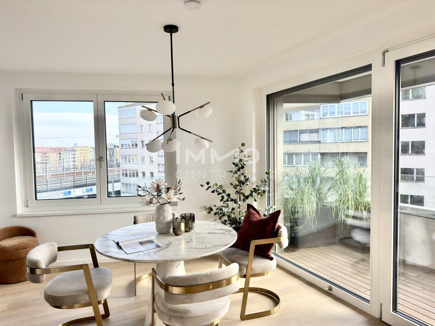 Essbereich mit elegantem Marmortisch und Stühlen, großen Fenstern und Blick auf den Balkon.