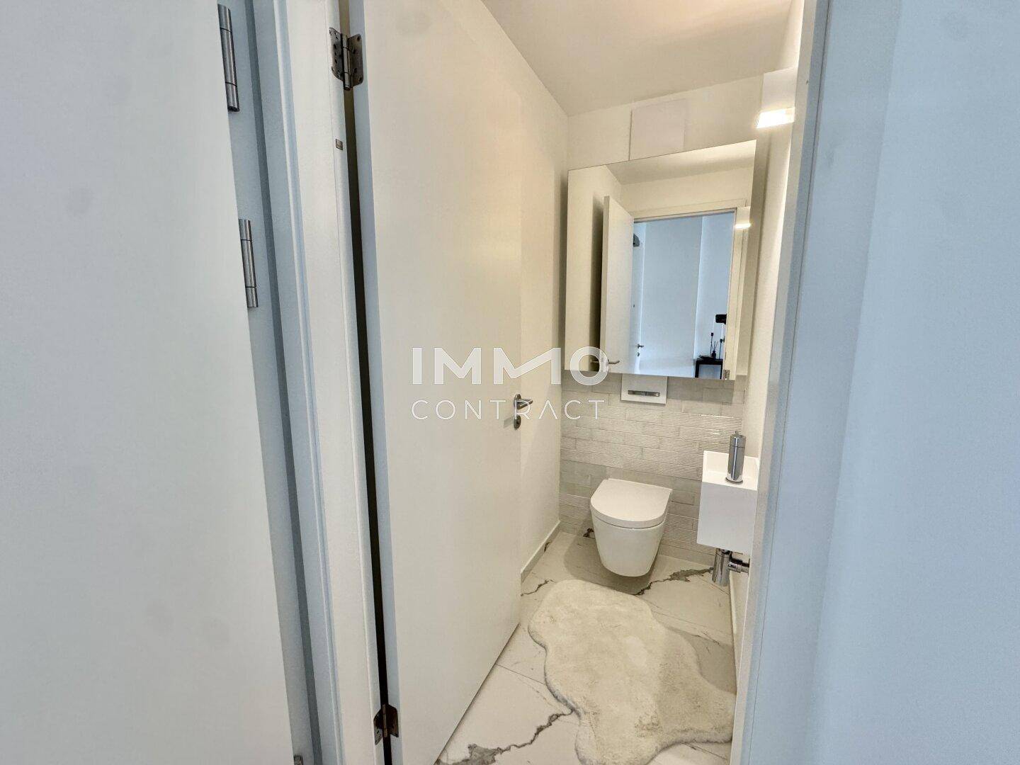 Modernes Gäste-WC mit wandhängender Toilette, kleinem Waschbecken und stilvollen Fliesen.