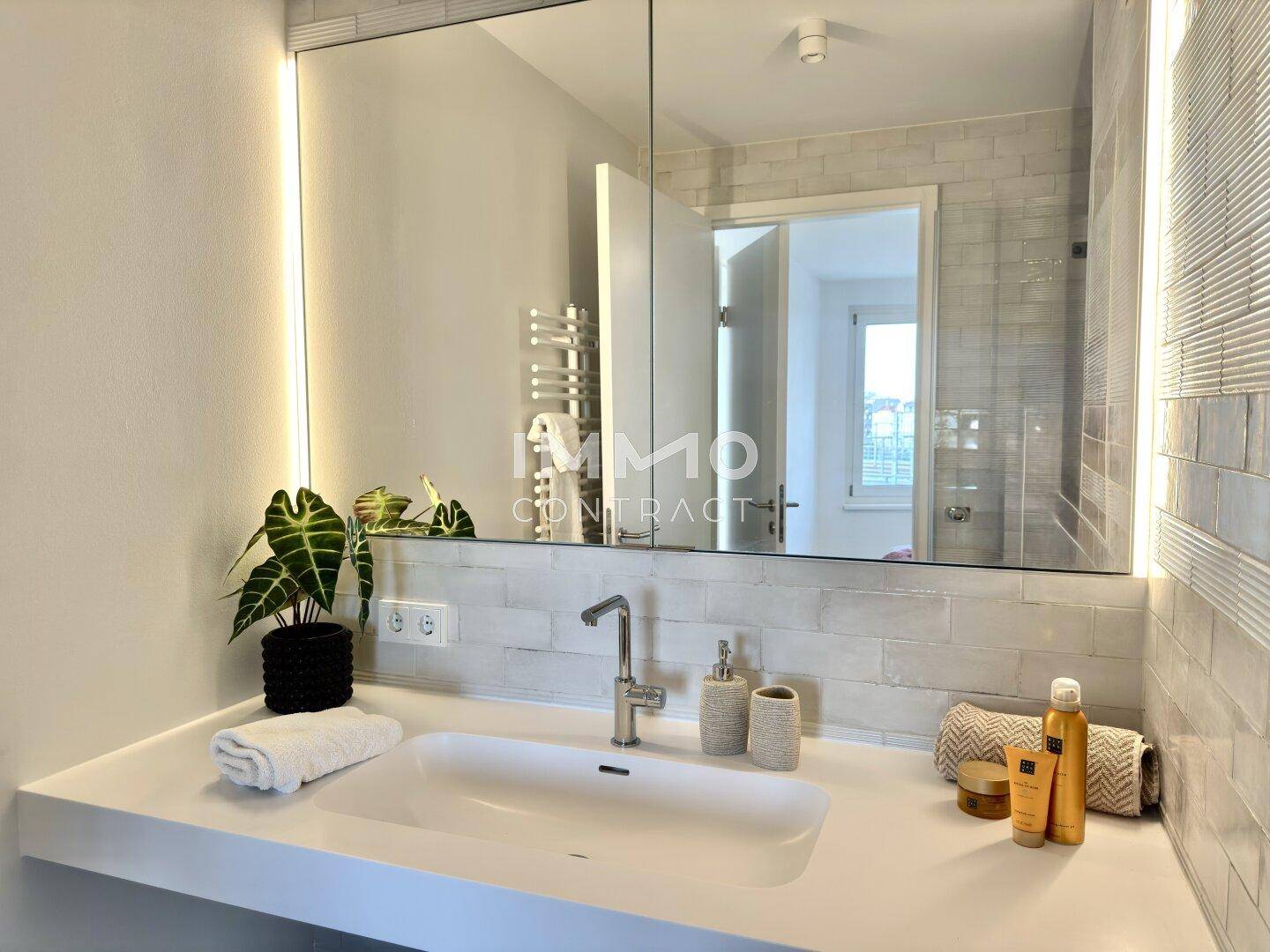 Detailansicht des modernen Badezimmers mit elegantem Waschbecken und beleuchtetem Spiegelschrank.