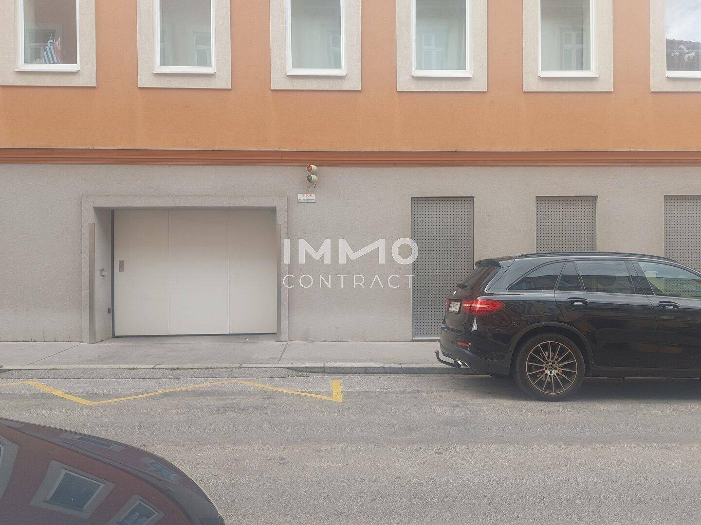 Fassade eines Gebäudes mit integrierter Garageneinfahrt und Fenstern im Obergeschoss.