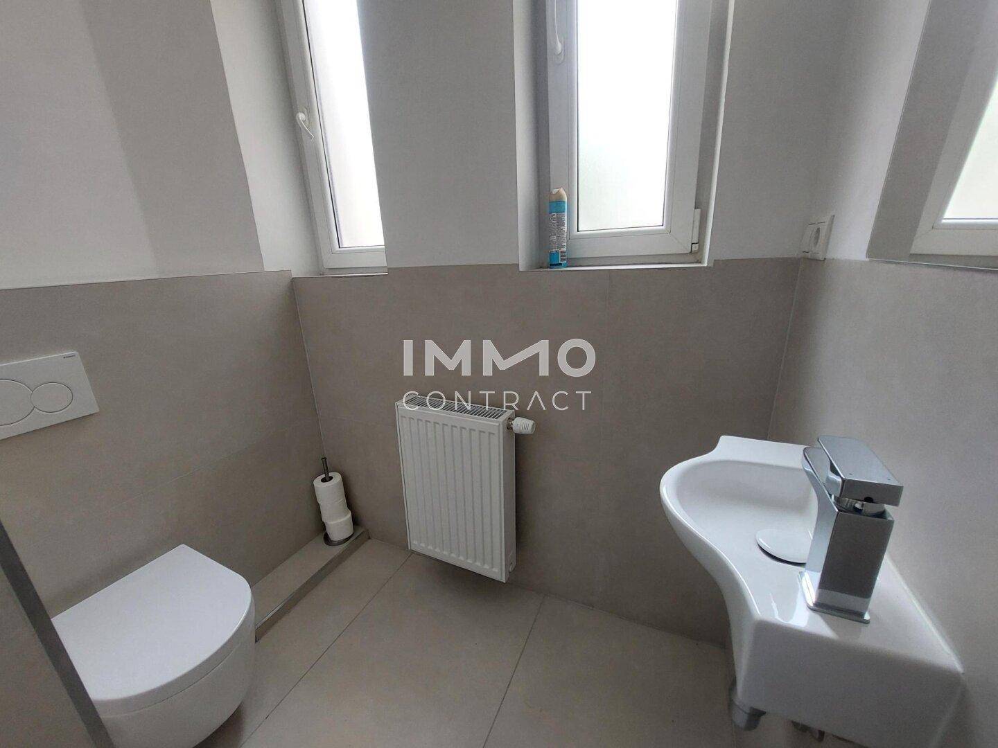 Separate Gästetoilette mit Fenster, wandhängendem WC und einem kleinen Waschbecken.