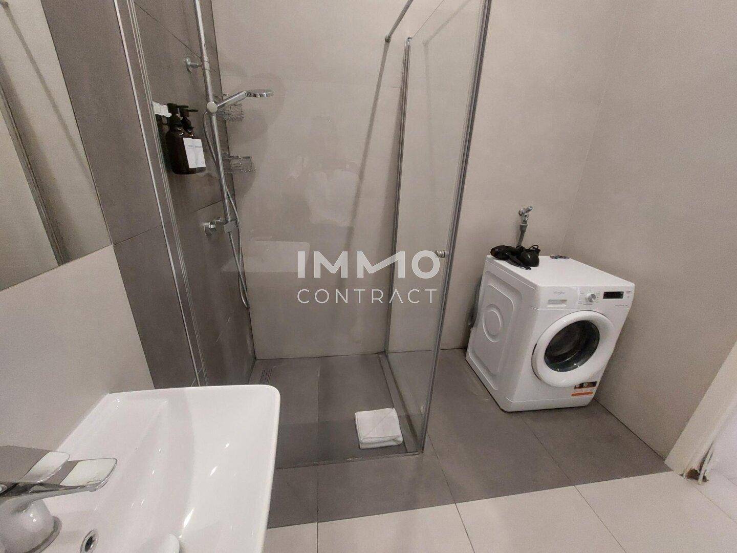 Helles Badezimmer mit großer Duschkabine, modernem Waschbecken und Fliesenboden.