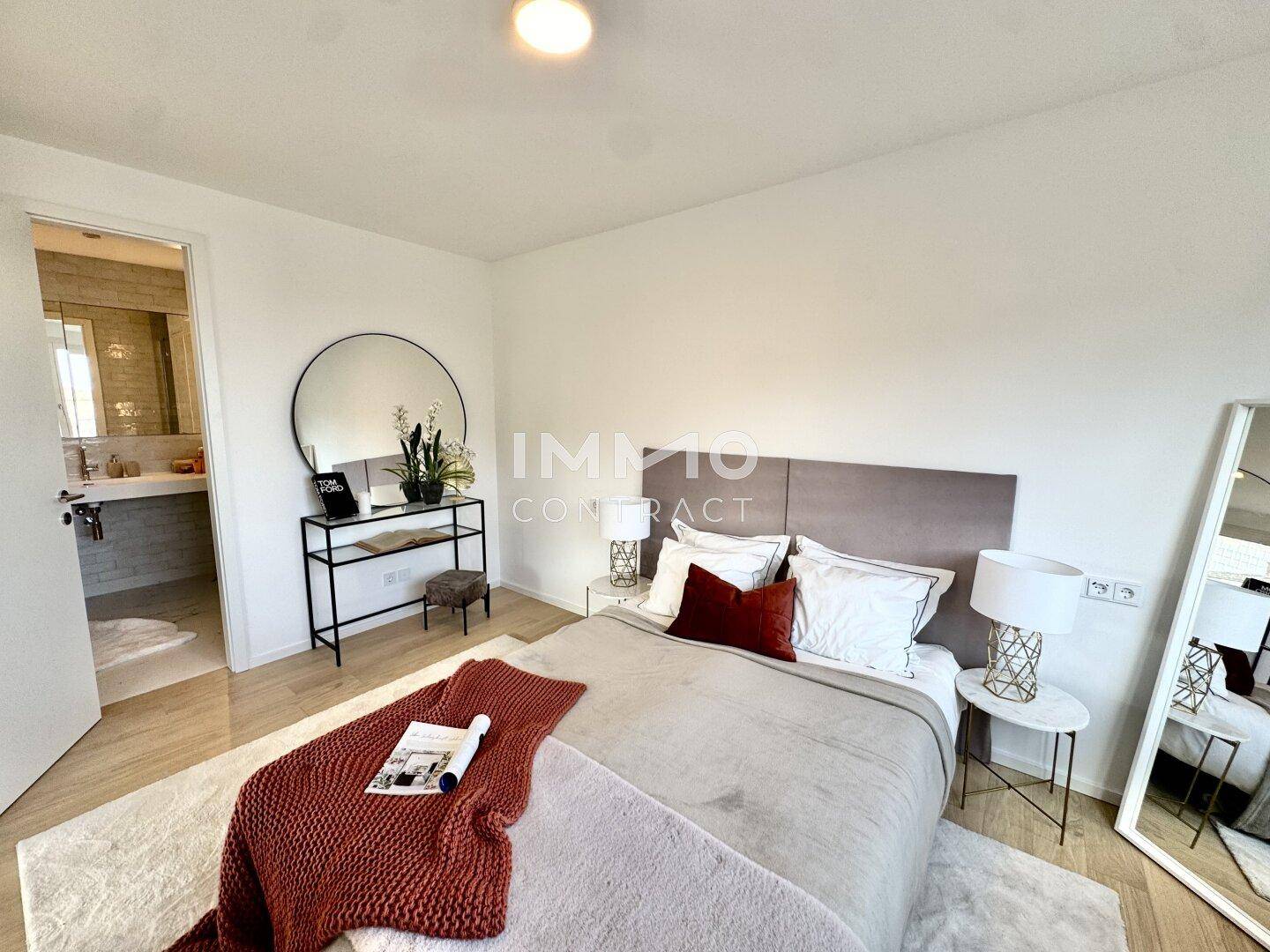 Modernes Schlafzimmer mit Doppelbett, Parkettboden und direktem Zugang zum Badezimmer.