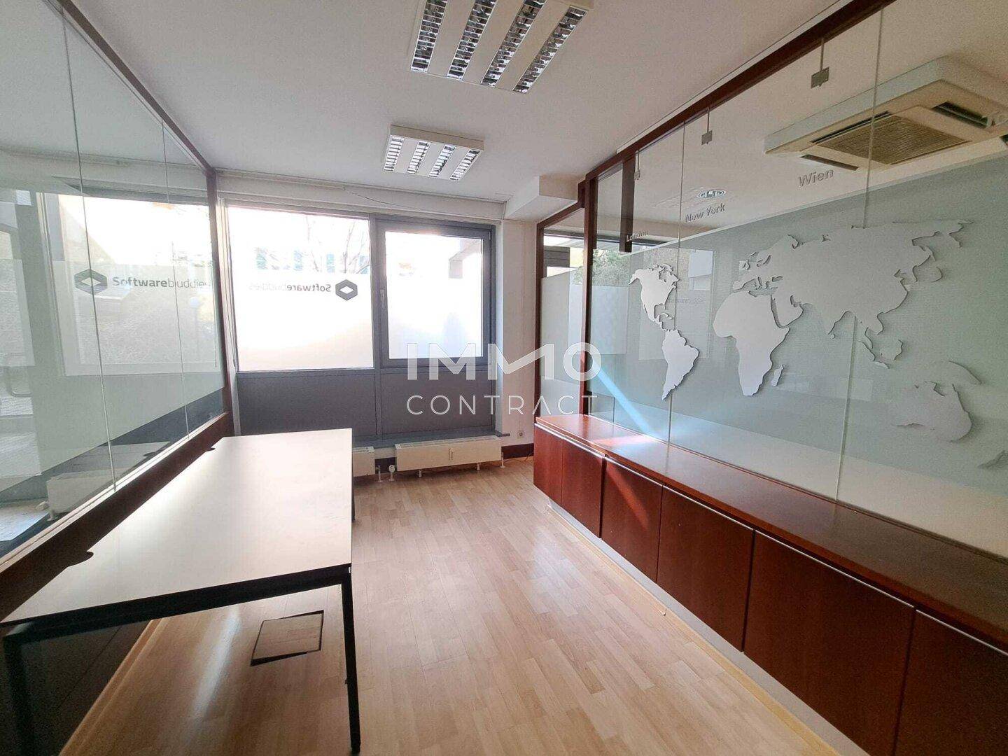 Modernes Büro mit Holzfußboden, großen Fenstern und einer Wanddekoration in Form einer Weltkarte.