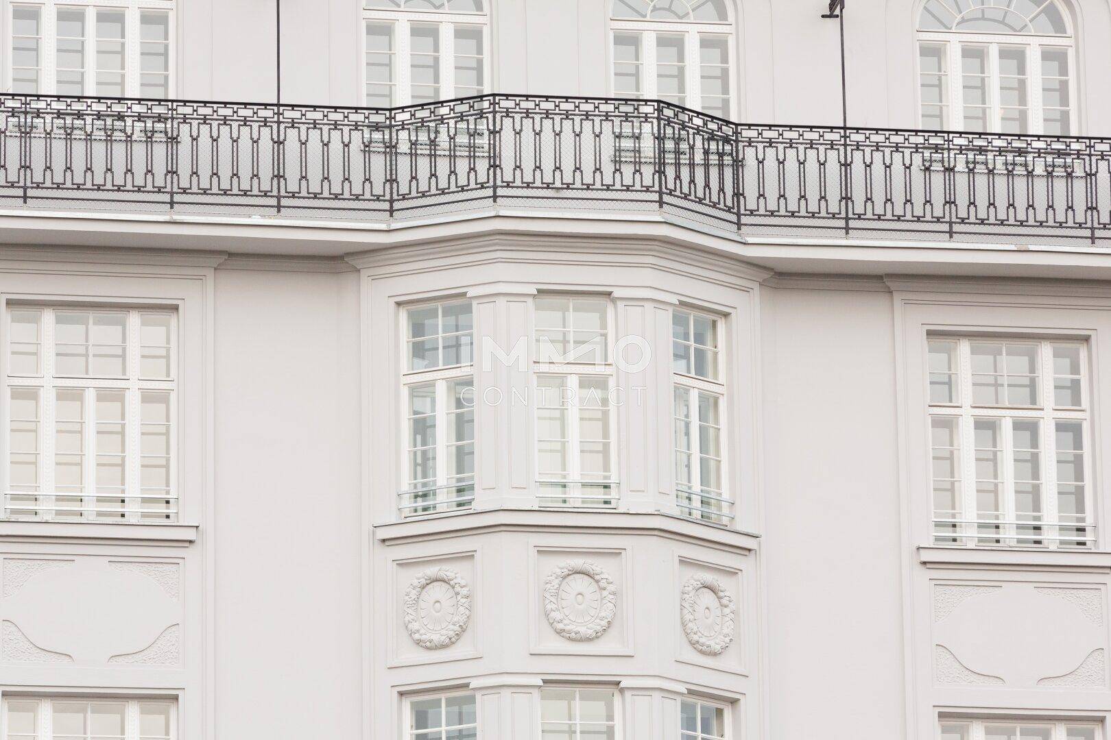 Elegante Gebäudefassade mit einem markanten Erker und einem schmiedeeisernen Balkon im oberen Bereich.