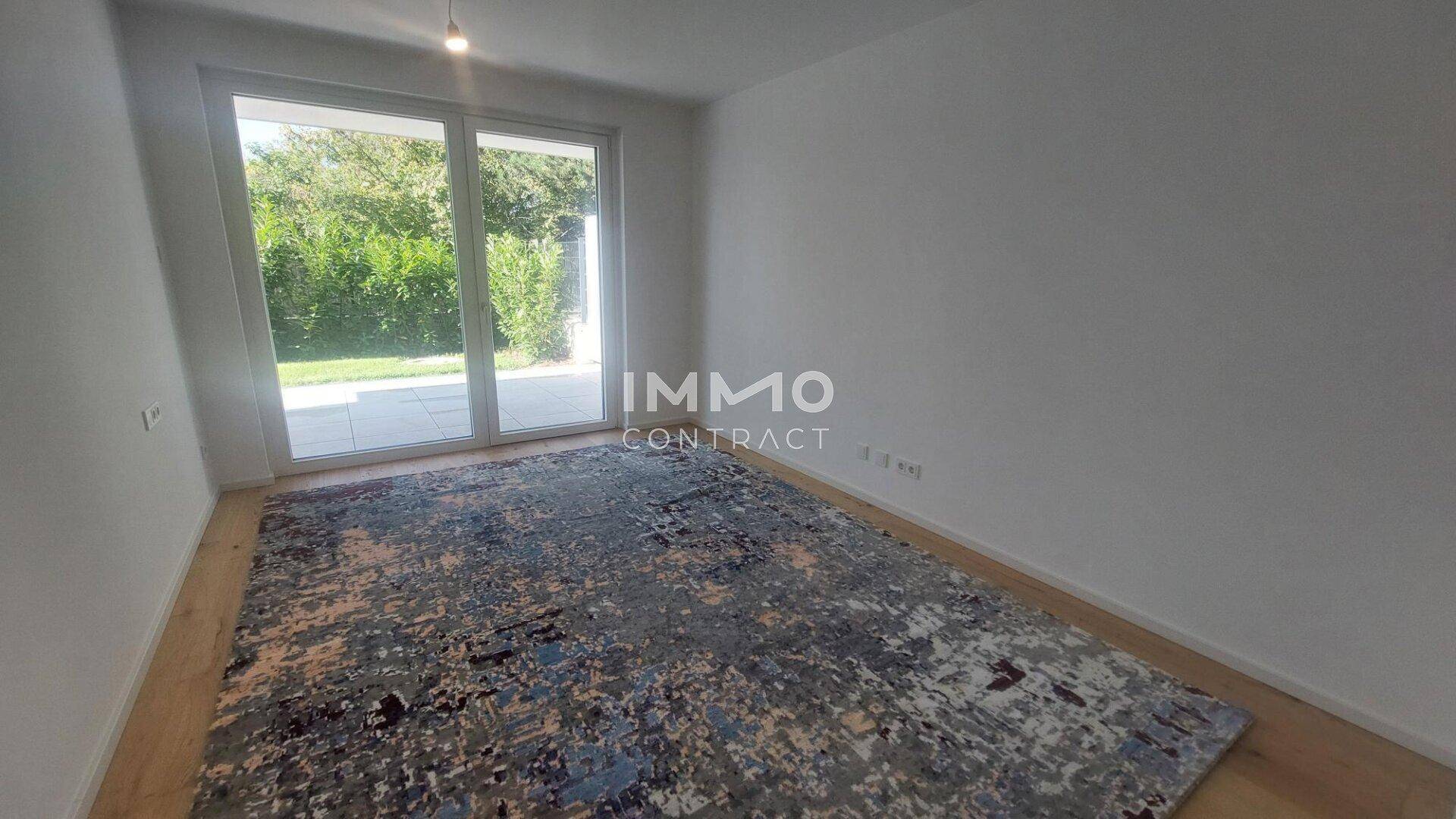 Helles Zimmer mit Holzboden und Zugang zu einem Außenbereich, ideal als Schlaf- oder Arbeitszimmer.