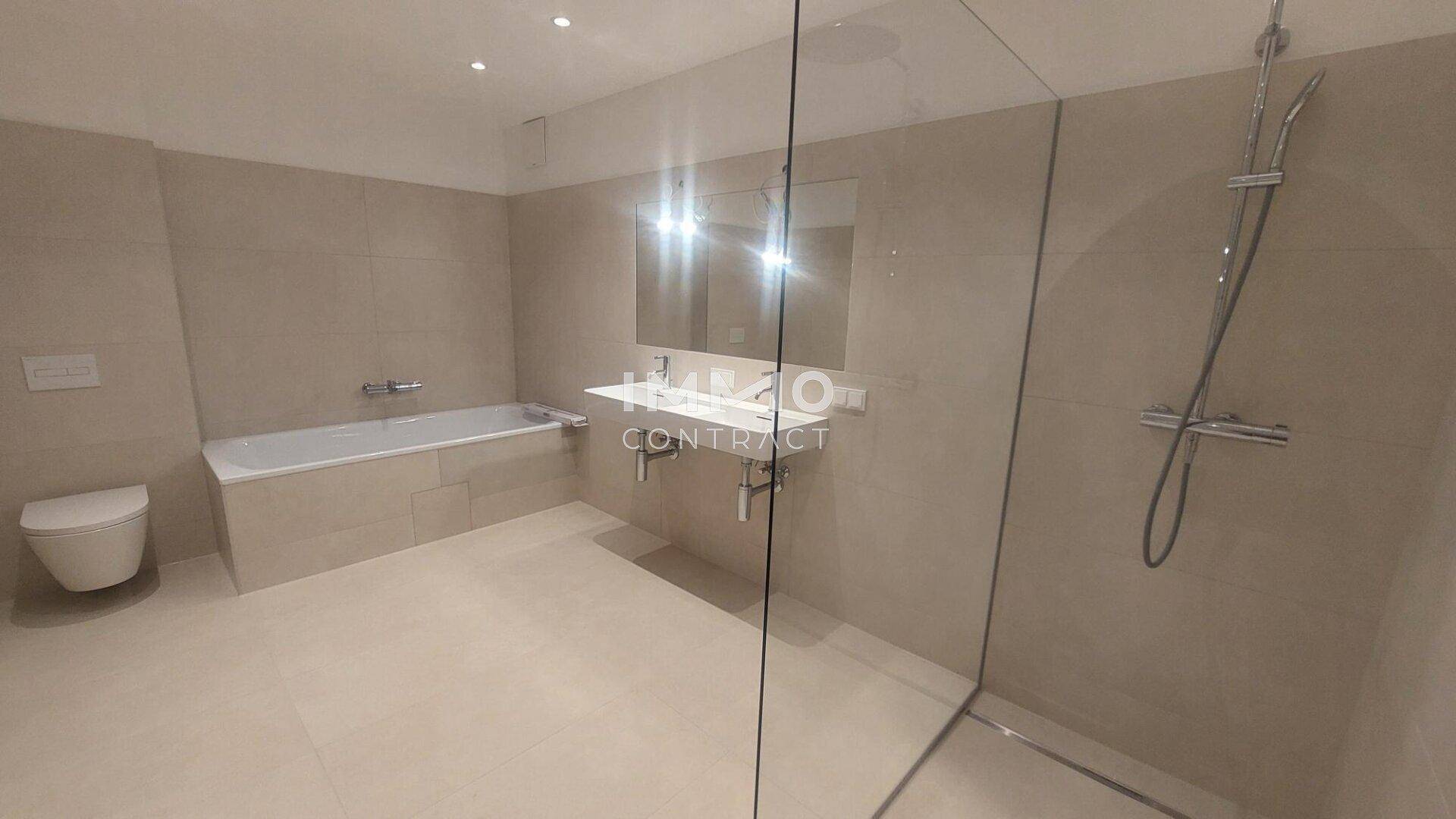 Geräumiges Badezimmer mit Badewanne, großer begehbarer Dusche und modernem Waschtisch.