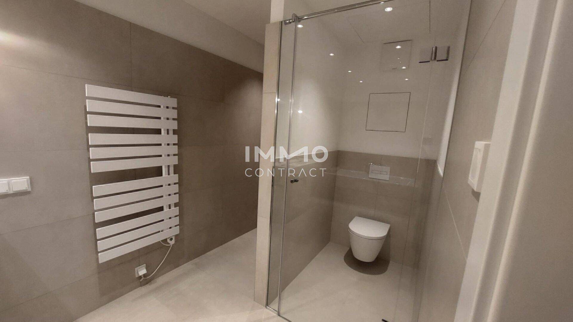 Zeitgemäßes Badezimmer mit begehbarer Dusche, Wand-WC und beheiztem Handtuchhalter.