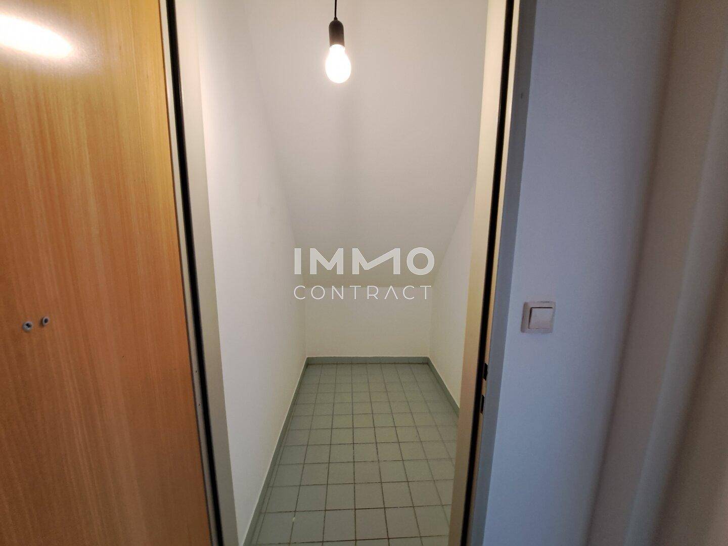 Kleiner, gefliester Abstellraum mit einfacher Beleuchtung.