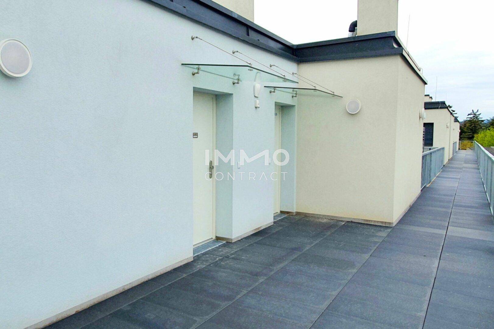 Außenbereich mit Fliesenboden, Glasvordach über den Eingängen und Zugang zu weiteren Wohneinheiten.