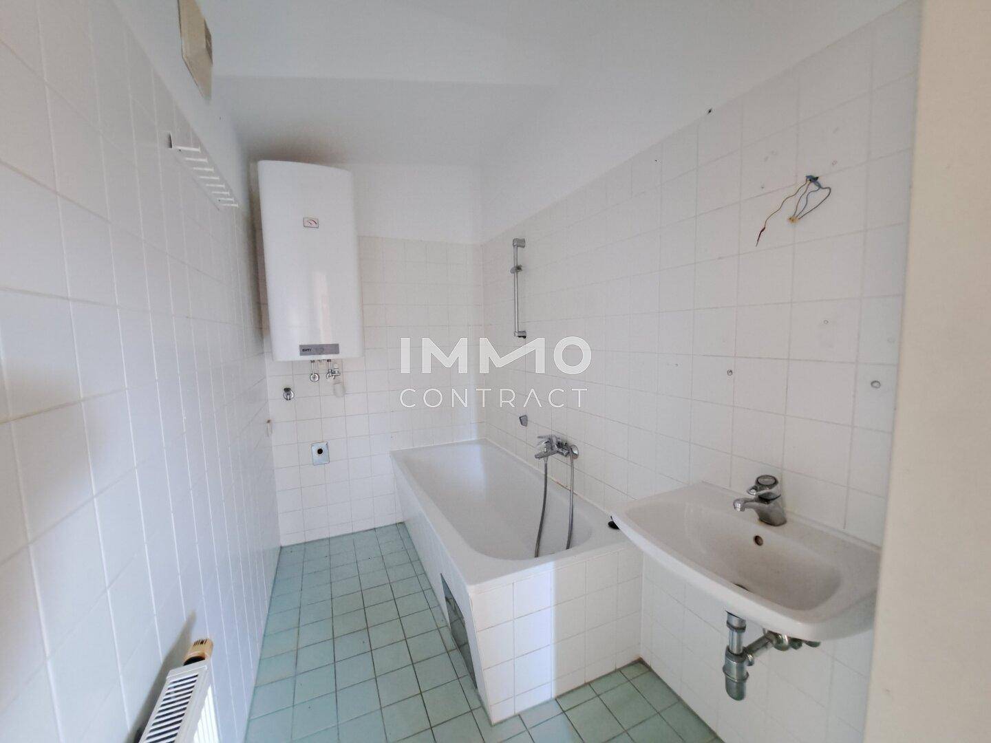 Badezimmer mit Badewanne, Waschbecken und weißen Wandfliesen.