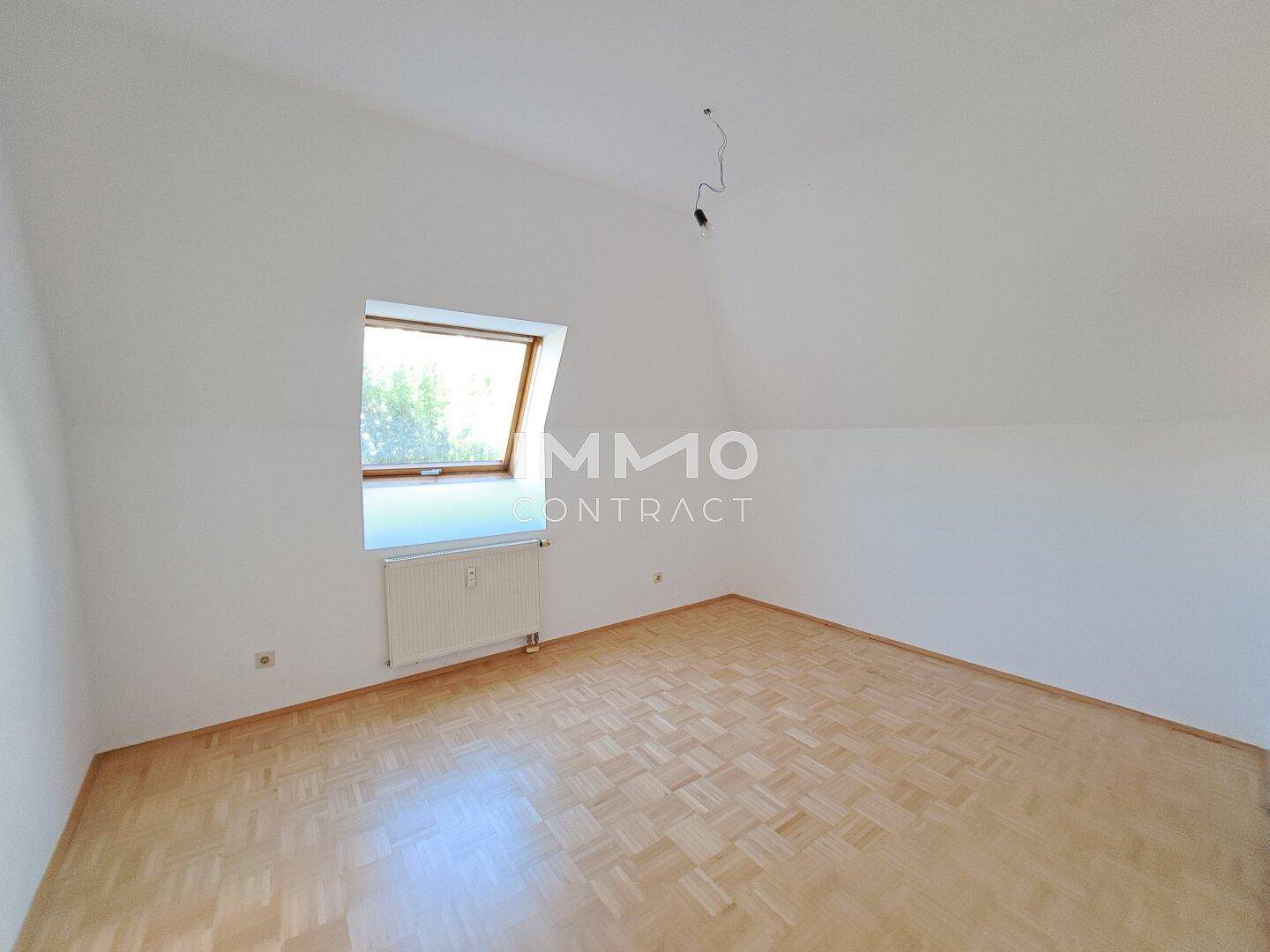 Heller Raum im Dachgeschoss mit Holzboden und einem großen Dachfenster.