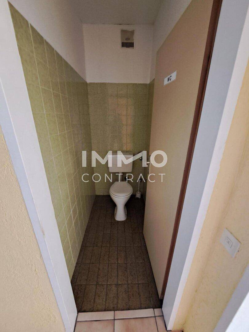 Toilettenraum mit WC, gefliesten Wänden in Grün und einfacher Ausstattung.