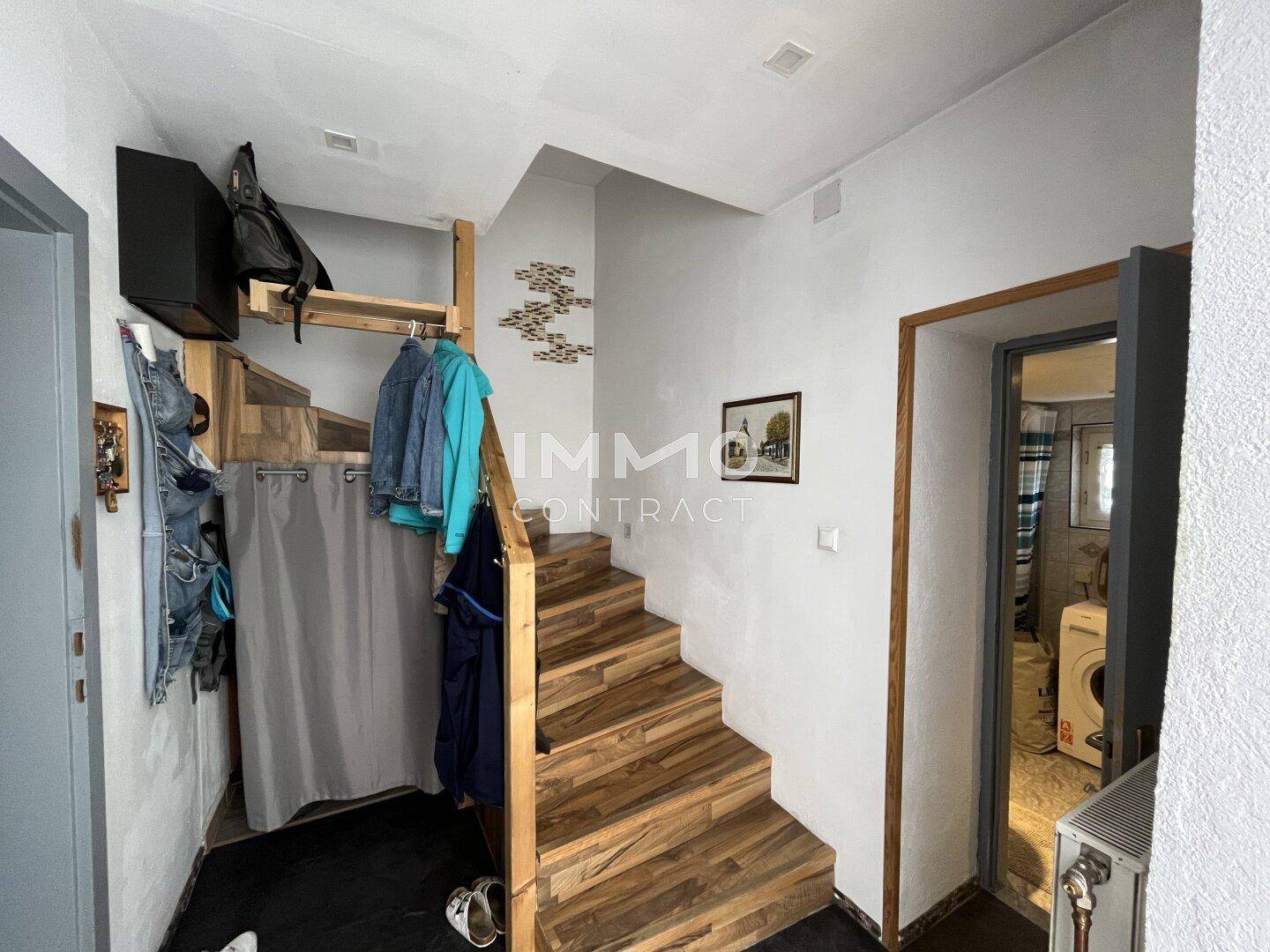 Eingangsbereich mit Holztreppe und Garderobe, die zu den oberen Etagen führt.