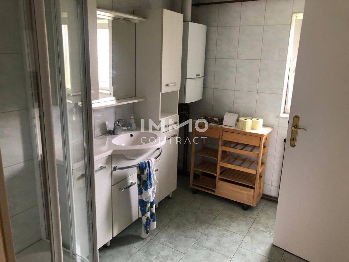 Funktionales Badezimmer mit Duschkabine, Waschbecken und Wandfliesen in hellem Grün.