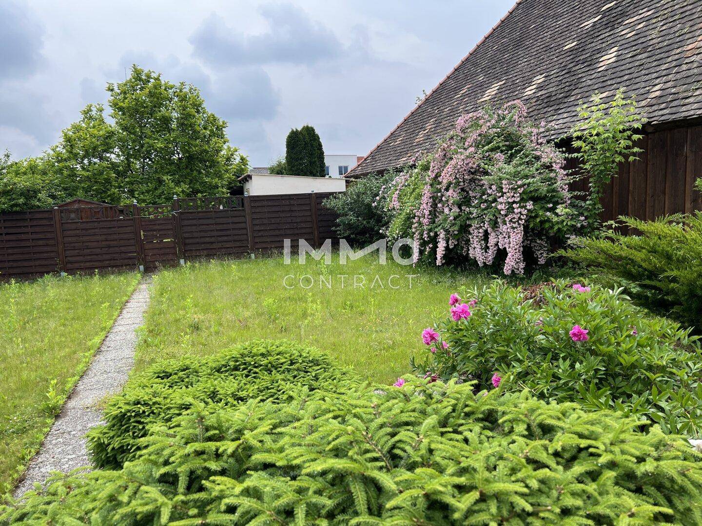 Gepflegter Gartenbereich mit verschiedenen Sträuchern und einem schmalen Steinweg.