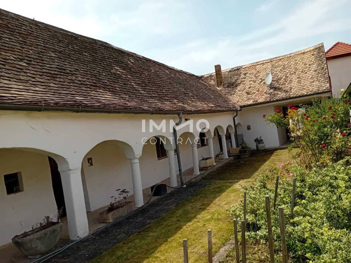 Sonniger Innenhof mit blühenden Rosen und traditioneller Architektur, ideal zum Entspannen.