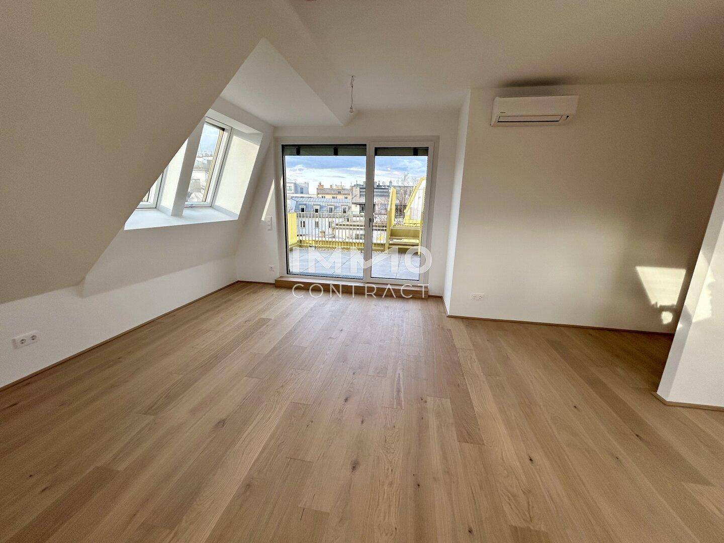 Heller Wohnbereich im Dachgeschoss mit Zugang zu einem Balkon und moderner Klimaanlage.