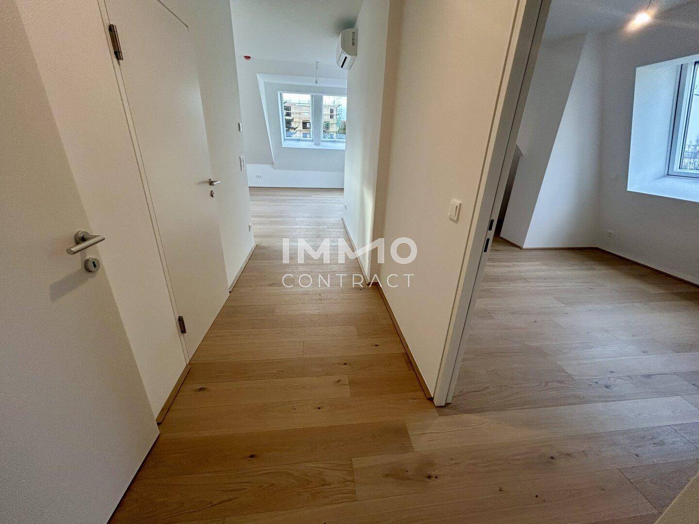 Heller Flur mit Holzboden und weißen Türen, der zu verschiedenen Zimmern im Dachgeschoss führt.