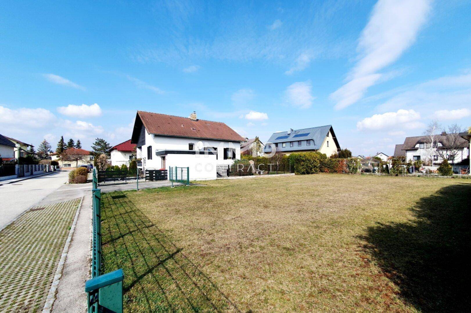 Unbebautes Grundstück mit Rasenfläche und angrenzender Straße in einer Wohngegend.