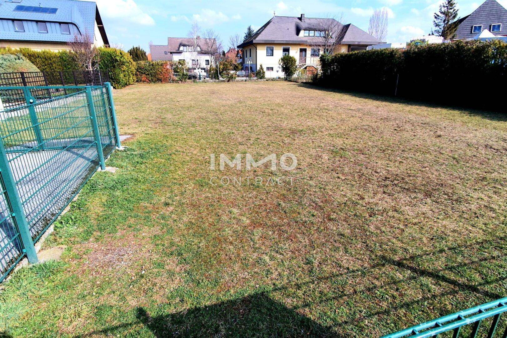 Unbebautes Grundstück mit Rasenfläche und angrenzenden Häusern, ideal für Neubauprojekte.