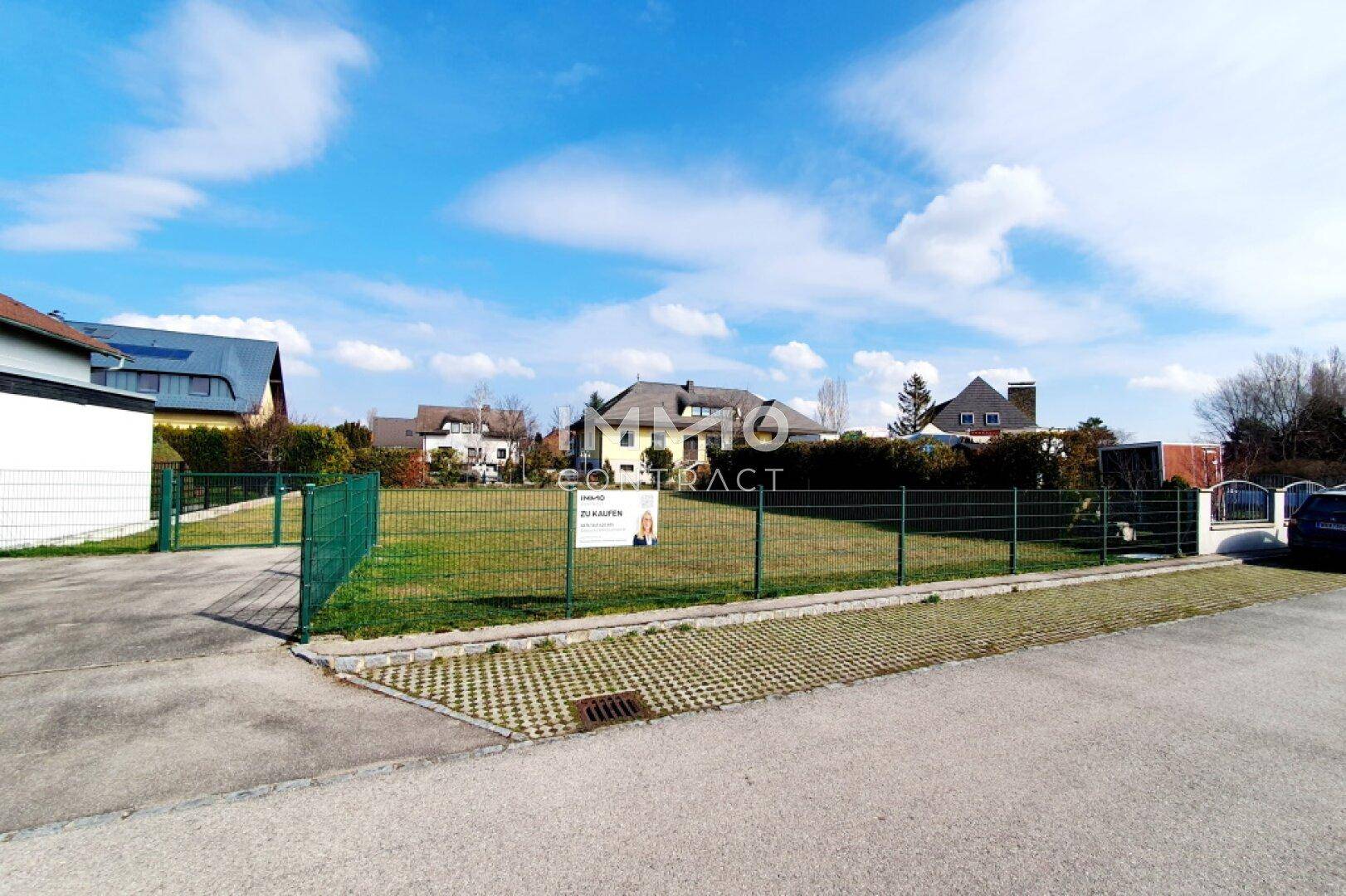 Weitläufiges Grundstück mit Zaun und angrenzender Straße, bereit zur Bebauung.