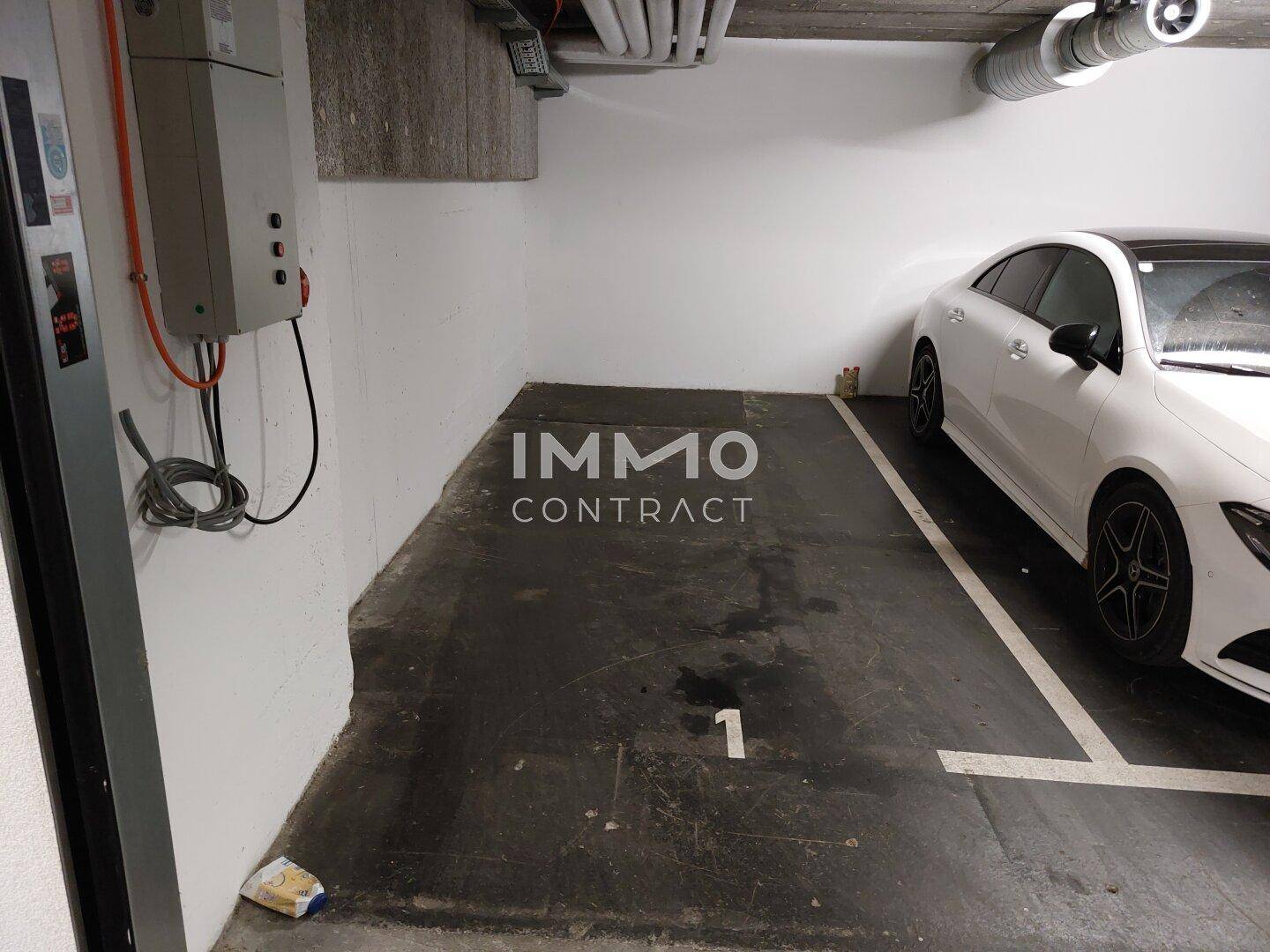 Tiefgarage mit einem weißen Auto und elektrischen Installationen an der Wand.