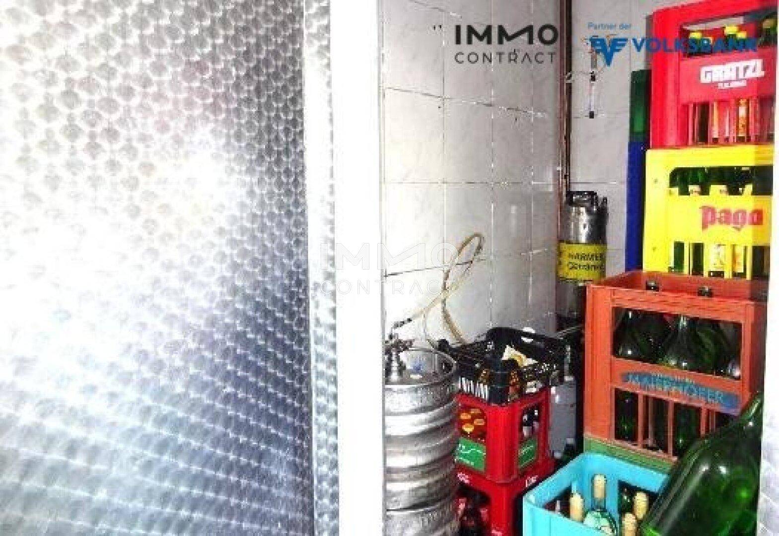 Lagerraum mit Getränkefässern und Kisten, gefliesten Wänden und Metallverkleidung.