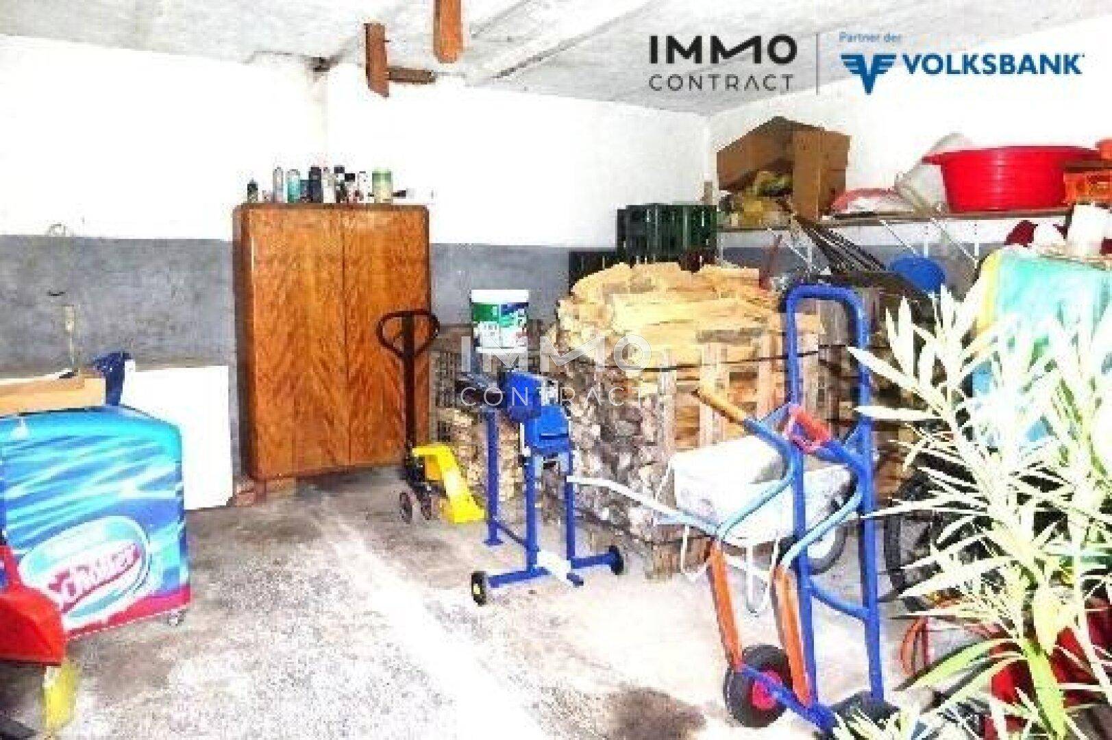 Großer Lagerraum mit Holzstapel, Transportwagen und verschiedenen Utensilien.