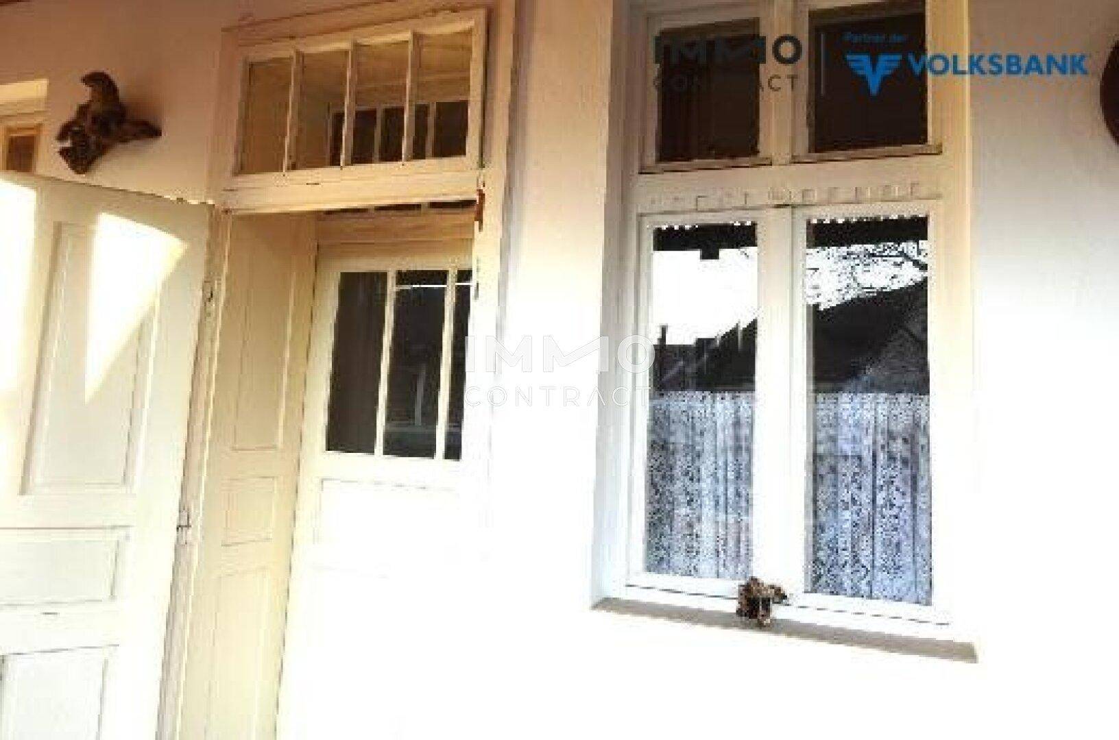 Nahaufnahme einer traditionellen weißen Holztür und eines Fensters mit Sprossen.