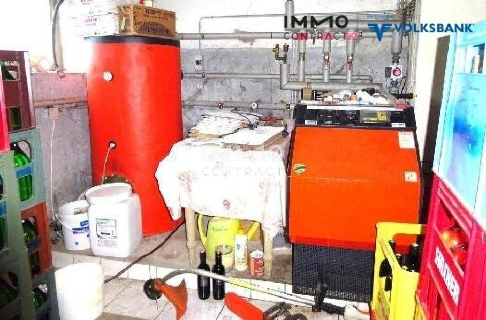 Heizungsraum mit Warmwasserspeicher, Heizkessel und Rohrleitungen.