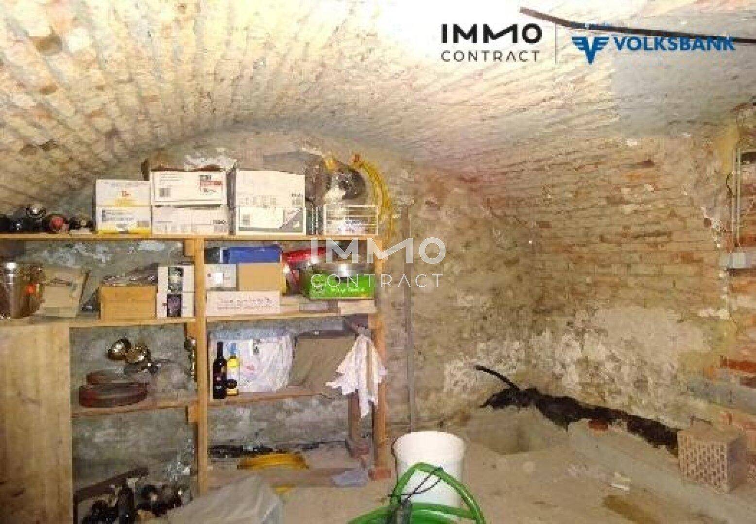 Historischer Gewölbekeller mit Ziegelwänden und Regalen für Lagerzwecke.