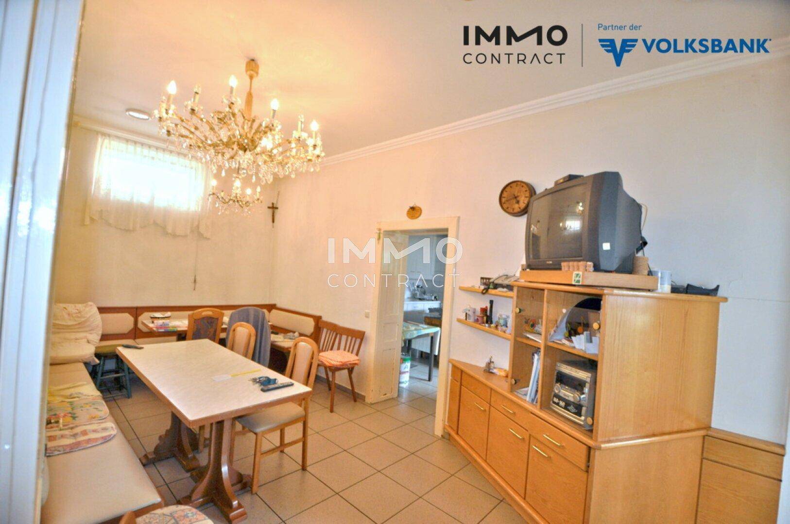 Traditioneller Essbereich mit großem Tisch, Eckbank und Kronleuchter, ausgestattet mit älteren Möbeln.