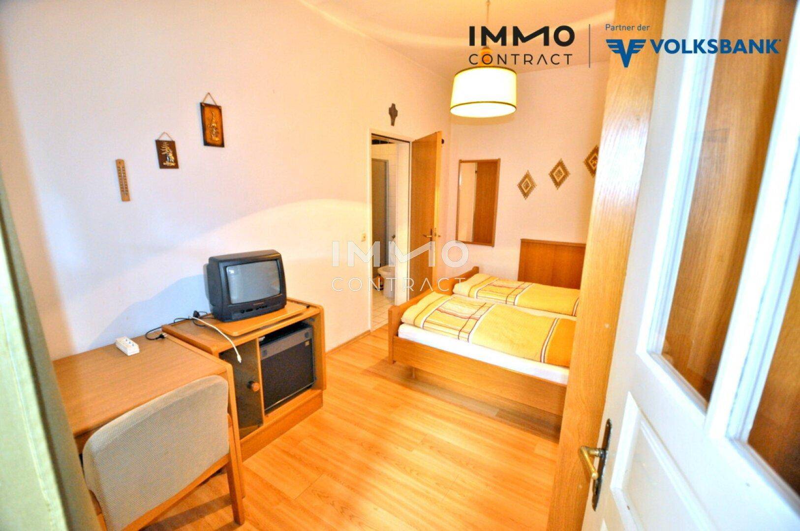 Gemütliches Doppelzimmer mit zwei Einzelbetten, Holzboden und einfacher Einrichtung.