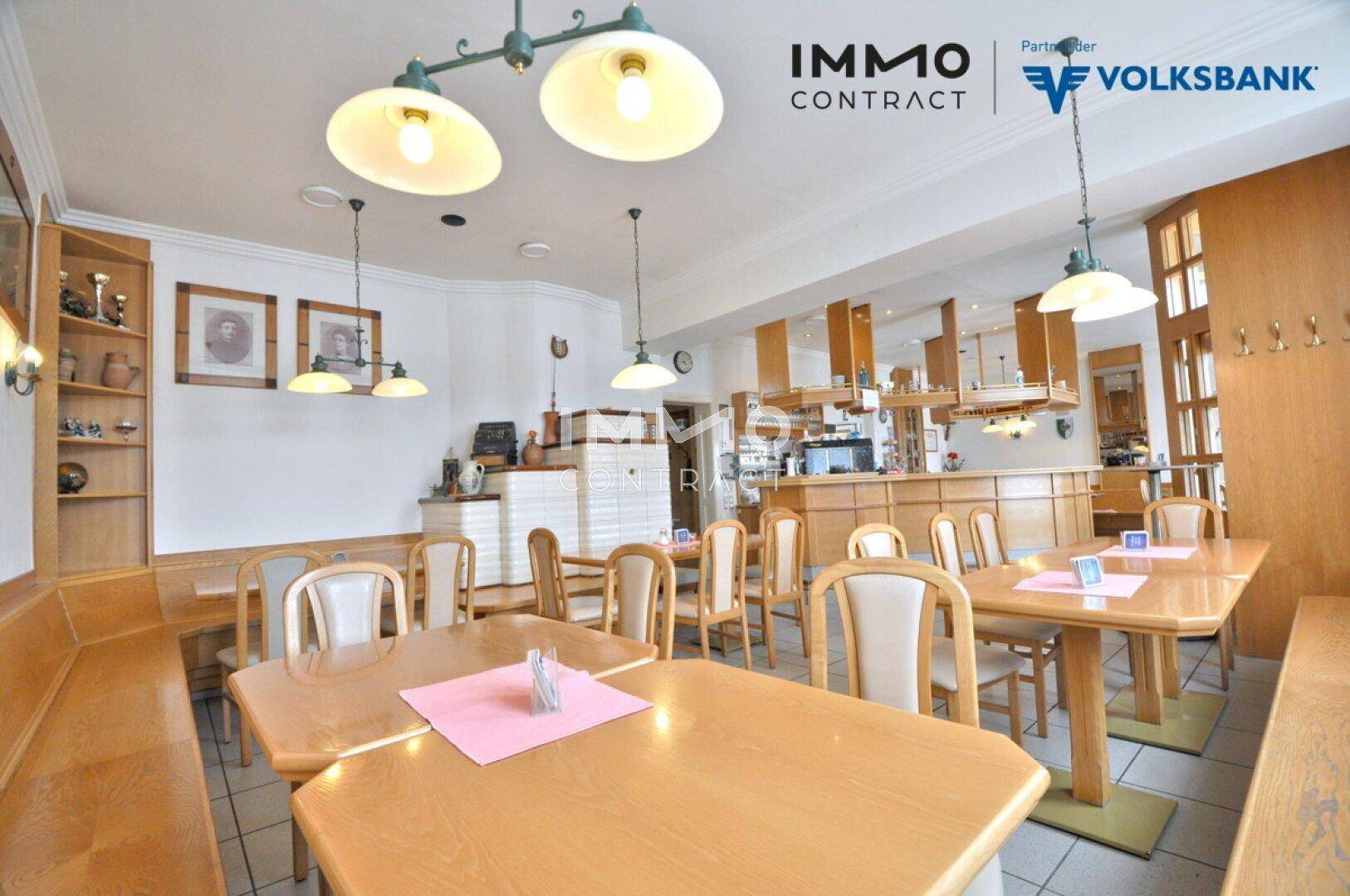 Gemütlicher Gastraum mit Holztischen, Stühlen und traditionellem Kachelofen.