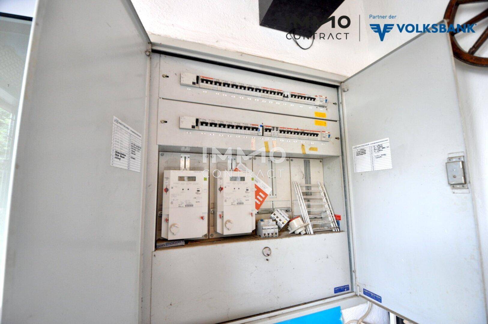 Offener Sicherungskasten mit mehreren Stromzählern und Schaltern.