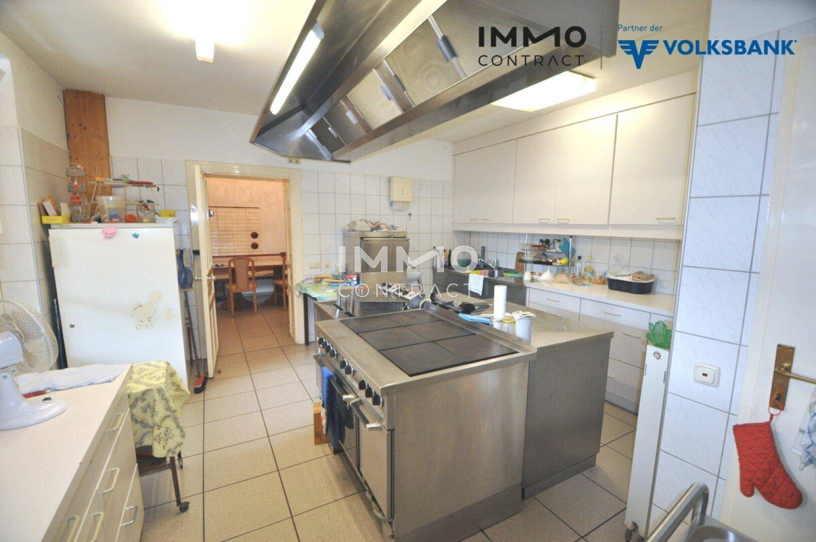 Geräumige Gewerbeküche mit Kochinsel, weißen Schränken und professionellen Geräten.